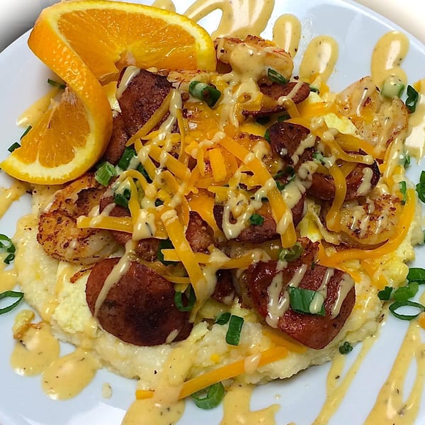 Sweet Berry Cafe's shrimp and grits with sausage, cheese, green onions, and an orange slice.