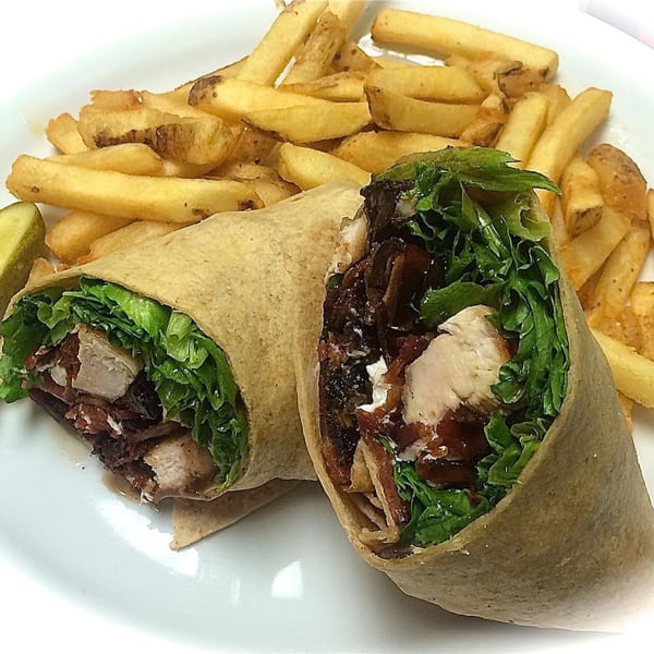 Sweet Berry Cafe's chicken wrap with lettuce and bacon, served with a side of golden french fries.